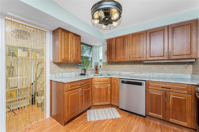 kitchen with light stone countertops, dishwasher, sink, tasteful backsplash, and light wood-type flooring