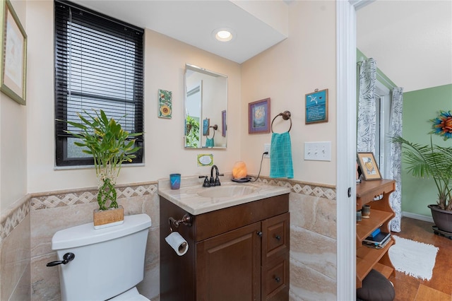 bathroom featuring vanity, toilet, and tile walls