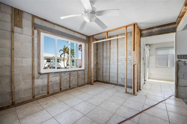 basement with ceiling fan and a textured ceiling