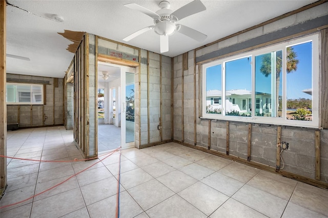 tiled empty room with ceiling fan and a textured ceiling