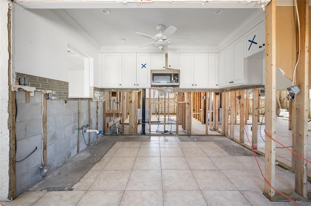 kitchen with white cabinets, ceiling fan, ornamental molding, and light tile patterned flooring