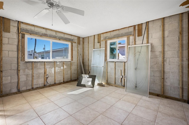 tiled spare room with a textured ceiling and ceiling fan