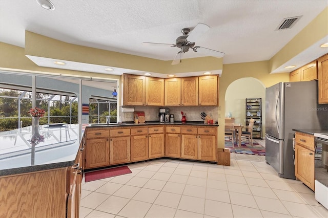 kitchen featuring tasteful backsplash, stainless steel refrigerator, ceiling fan, and light tile patterned flooring