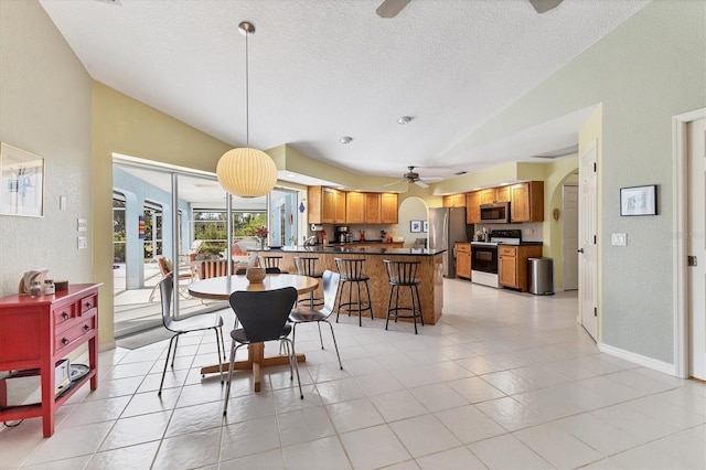 tiled dining room with ceiling fan and vaulted ceiling