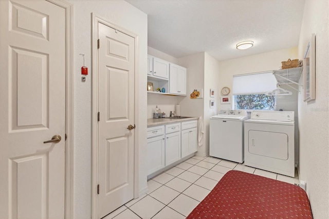 laundry area featuring cabinets, a textured ceiling, sink, light tile patterned floors, and washing machine and dryer