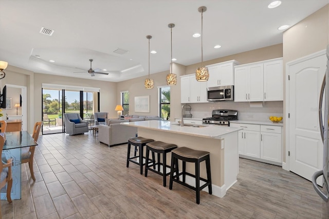 kitchen featuring ceiling fan, white cabinetry, a kitchen island with sink, and appliances with stainless steel finishes