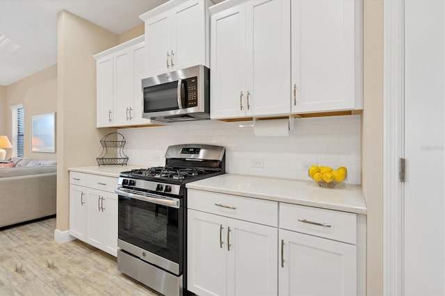 kitchen featuring white cabinets, decorative backsplash, light wood-type flooring, and stainless steel appliances