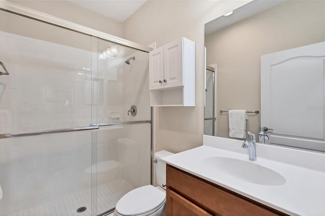 bathroom featuring vanity, toilet, and a shower with shower door