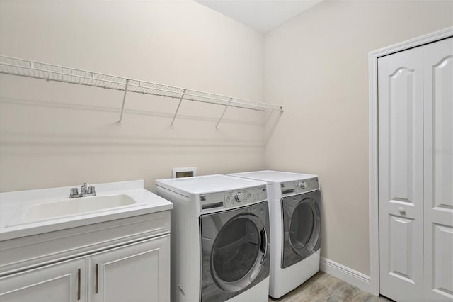 clothes washing area featuring light hardwood / wood-style floors, cabinets, independent washer and dryer, and sink