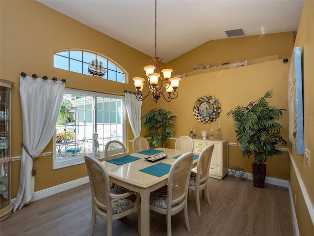 dining area featuring hardwood / wood-style floors, vaulted ceiling, plenty of natural light, and a notable chandelier