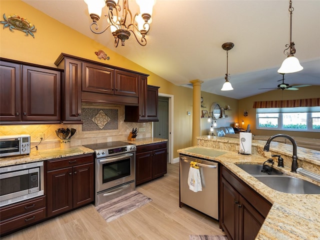 kitchen with light wood-type flooring, stainless steel appliances, vaulted ceiling, sink, and decorative light fixtures