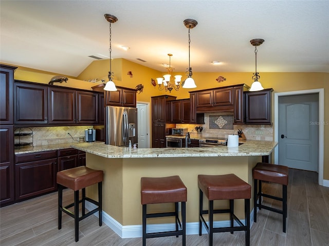 kitchen featuring a kitchen breakfast bar, dark brown cabinets, stainless steel appliances, and lofted ceiling