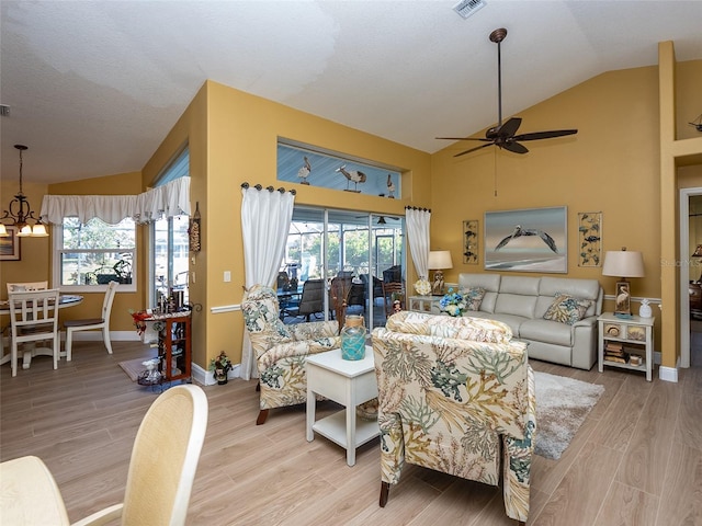 living room with hardwood / wood-style floors, ceiling fan with notable chandelier, a healthy amount of sunlight, and lofted ceiling