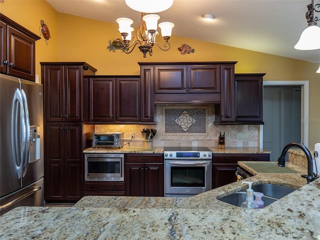 kitchen featuring pendant lighting, sink, vaulted ceiling, decorative backsplash, and appliances with stainless steel finishes