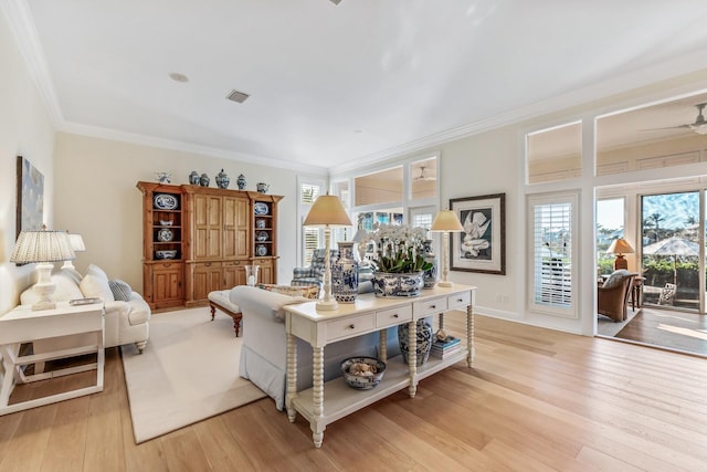 living room featuring ornamental molding, a healthy amount of sunlight, and light wood-type flooring