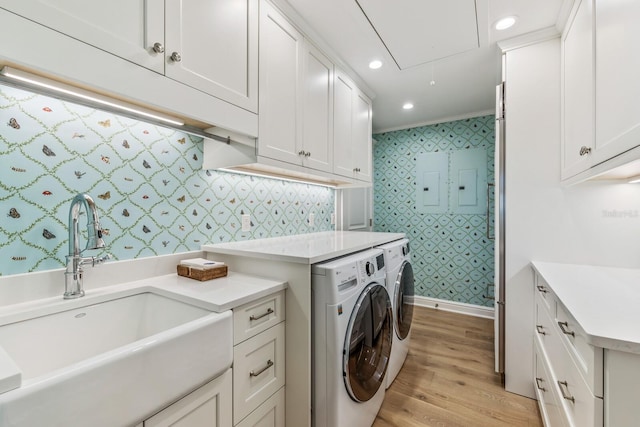 washroom with washer and dryer, light wood-type flooring, cabinets, and sink