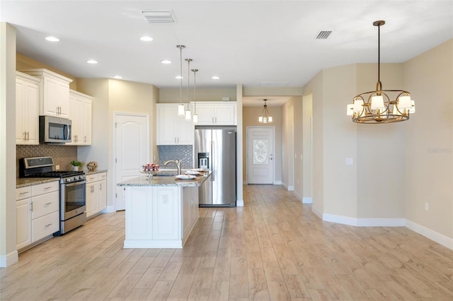 kitchen with light stone countertops, pendant lighting, stainless steel appliances, and light wood-type flooring