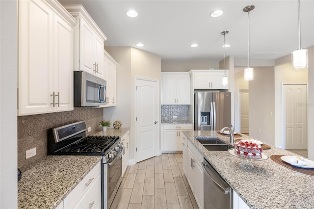 kitchen with light stone countertops, stainless steel appliances, white cabinetry, and sink