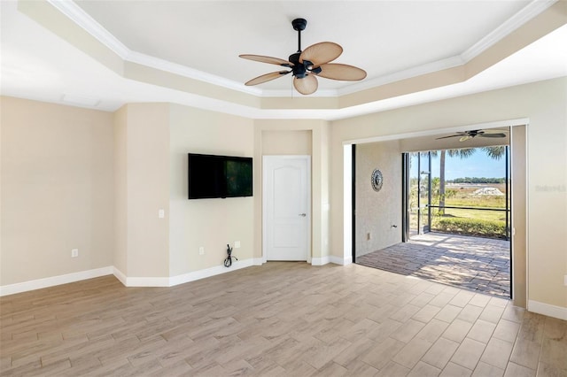 unfurnished living room with a raised ceiling, light wood-type flooring, and ornamental molding