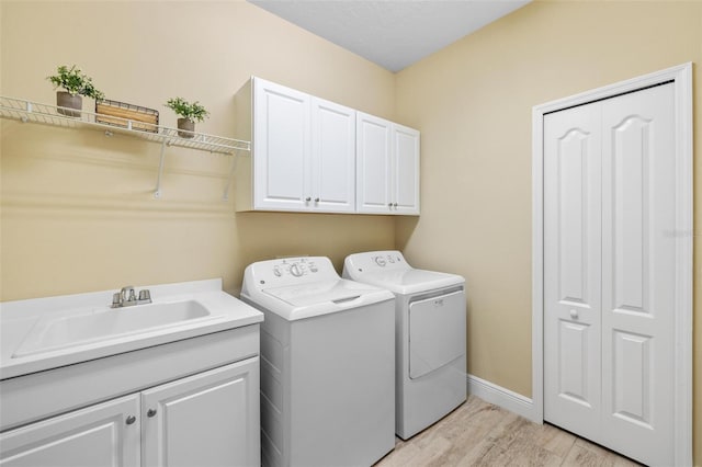 washroom featuring light hardwood / wood-style floors, cabinets, separate washer and dryer, and sink