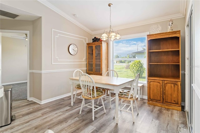 dining room with a chandelier, lofted ceiling, light hardwood / wood-style flooring, and ornamental molding