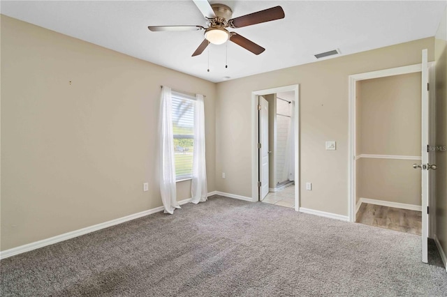 unfurnished bedroom with ensuite bath, ceiling fan, and light colored carpet