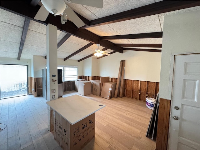 living room with vaulted ceiling with beams, ceiling fan, light hardwood / wood-style floors, and wood walls