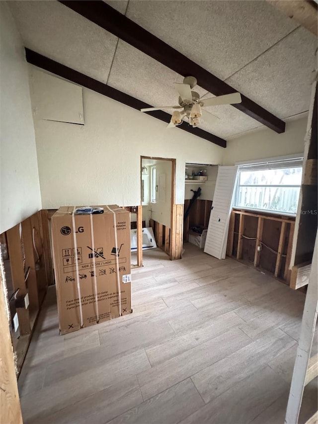 interior space with ceiling fan, lofted ceiling with beams, light wood-type flooring, and a textured ceiling