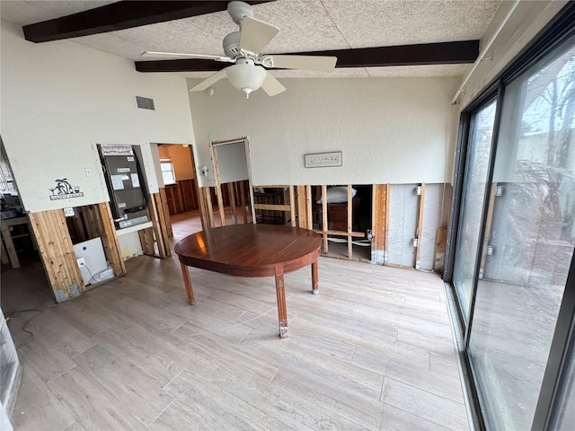 dining room featuring a textured ceiling, ceiling fan, light hardwood / wood-style flooring, vaulted ceiling with beams, and wood walls