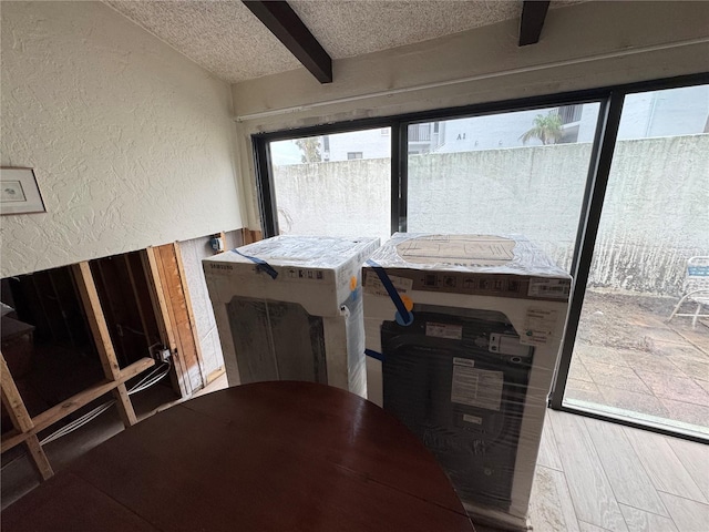 dining room featuring beamed ceiling, hardwood / wood-style floors, and a textured ceiling