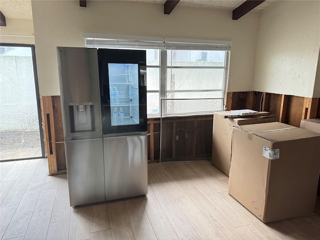 kitchen featuring beamed ceiling, light hardwood / wood-style floors, refrigerator, and stainless steel refrigerator with ice dispenser