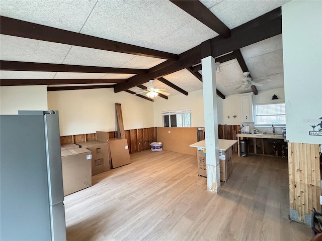 unfurnished living room with vaulted ceiling with beams, light wood-type flooring, and wood walls