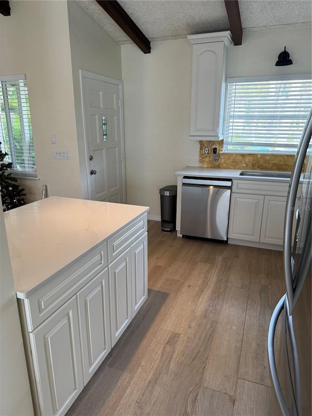 kitchen with white cabinets, appliances with stainless steel finishes, a textured ceiling, and beam ceiling