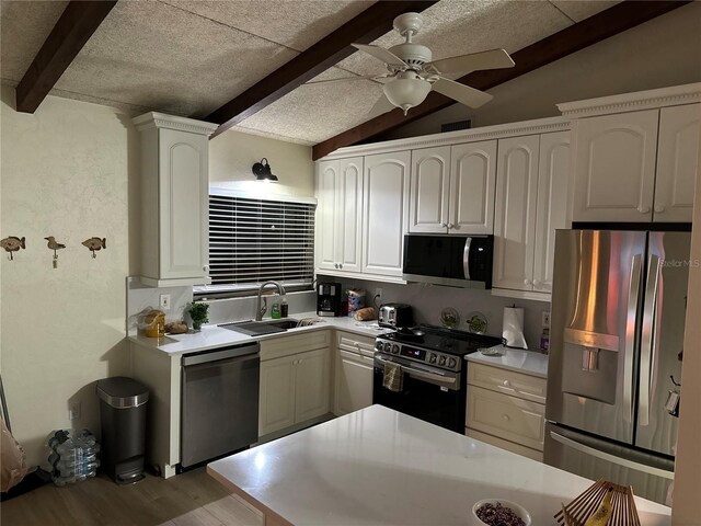 kitchen featuring sink, vaulted ceiling with beams, appliances with stainless steel finishes, light hardwood / wood-style floors, and white cabinetry