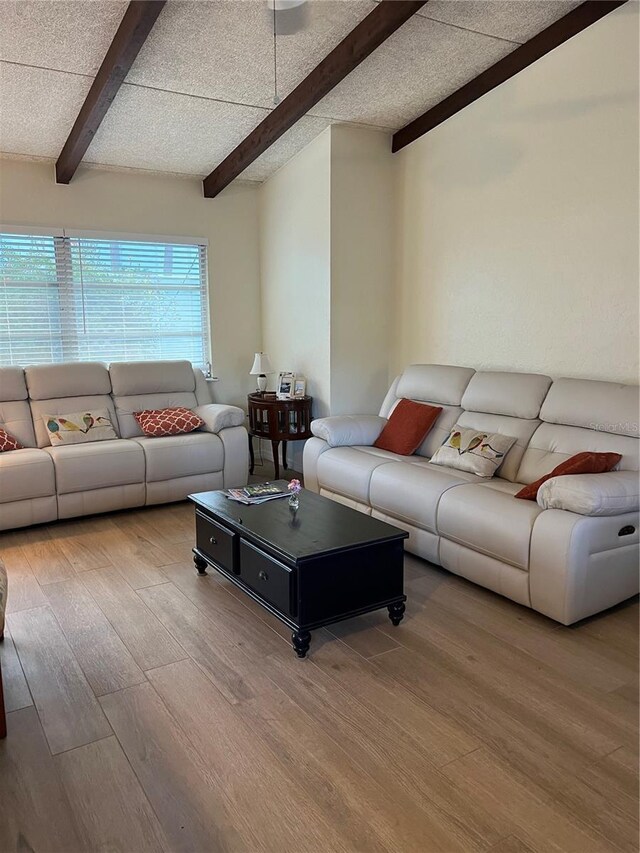 living room with beamed ceiling, a textured ceiling, and hardwood / wood-style flooring