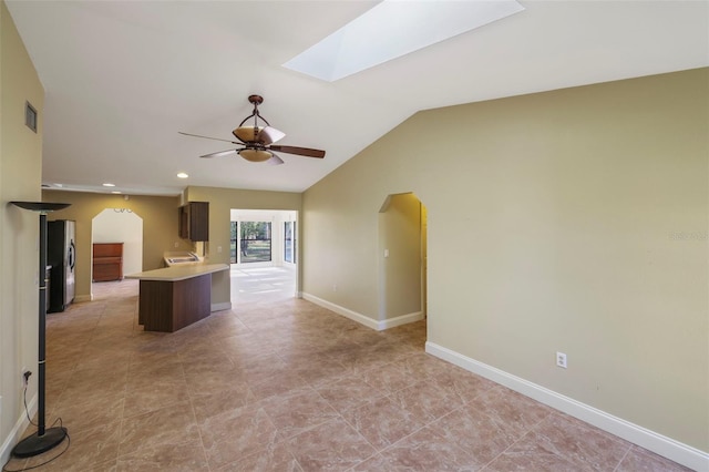 kitchen featuring ceiling fan, vaulted ceiling with skylight, and stainless steel refrigerator