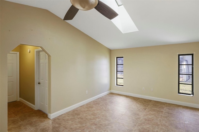 spare room with vaulted ceiling with skylight and ceiling fan