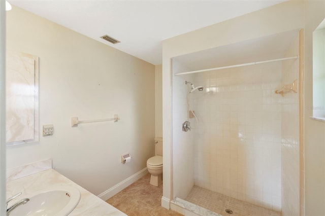 bathroom featuring vanity, toilet, tile patterned flooring, and a tile shower