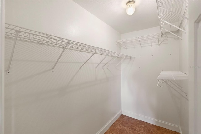 walk in closet with dark tile patterned flooring