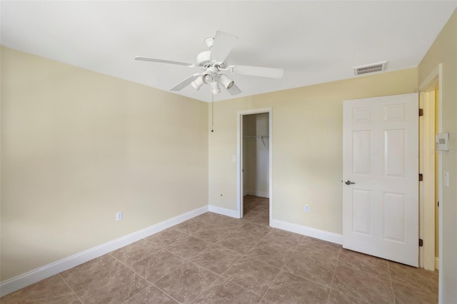 unfurnished bedroom with ceiling fan, a spacious closet, and a closet