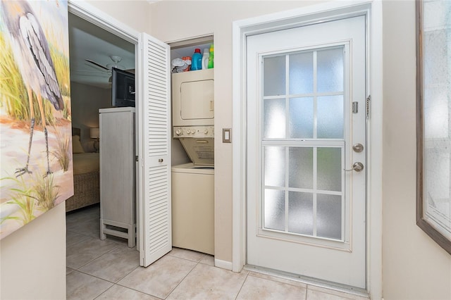 doorway to outside with stacked washer / dryer and light tile patterned floors