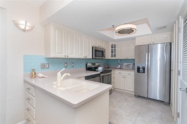 kitchen with kitchen peninsula, sink, white cabinets, and appliances with stainless steel finishes