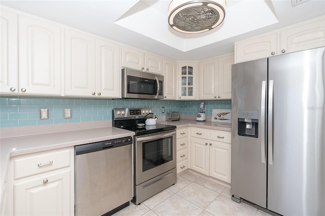 kitchen featuring white cabinets, a raised ceiling, light tile patterned floors, tasteful backsplash, and stainless steel appliances