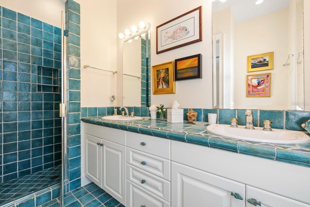 bathroom with tile patterned floors, vanity, and a tile shower