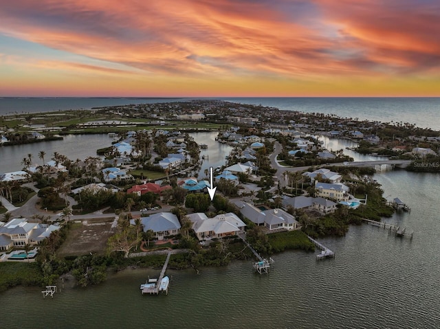 aerial view at dusk featuring a water view