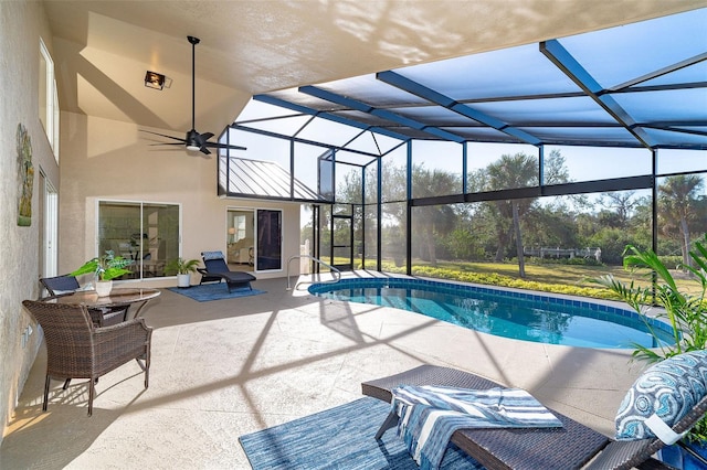 view of pool with a patio, glass enclosure, and ceiling fan