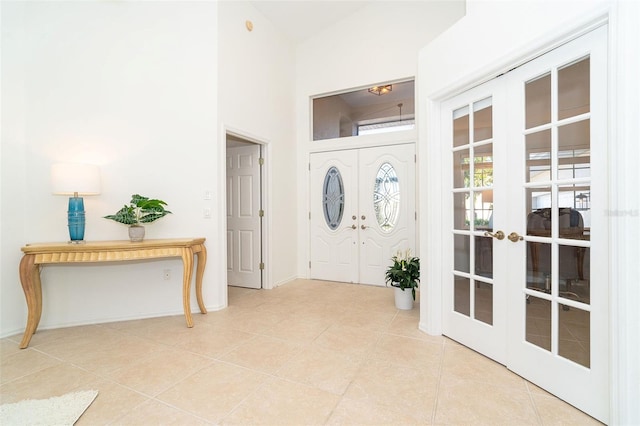 entryway featuring a high ceiling, light tile patterned floors, and french doors