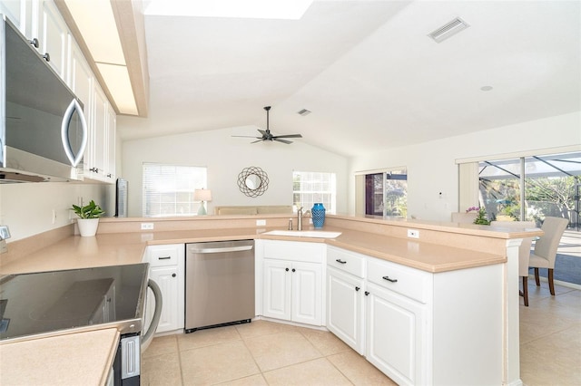 kitchen featuring sink, stainless steel appliances, white cabinets, vaulted ceiling, and kitchen peninsula