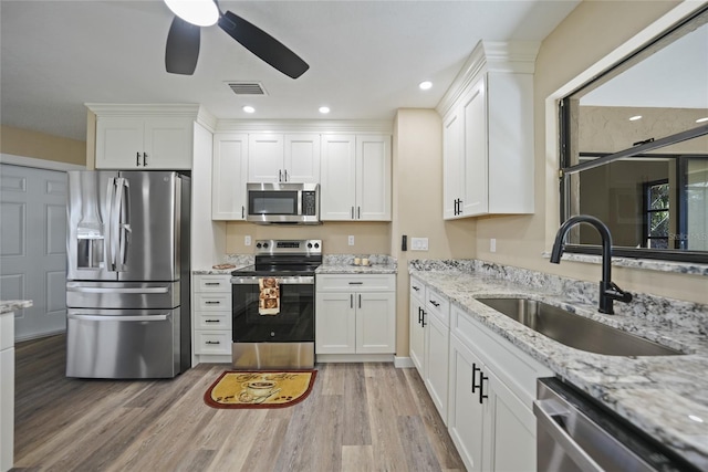 kitchen with white cabinets, sink, appliances with stainless steel finishes, and light hardwood / wood-style flooring