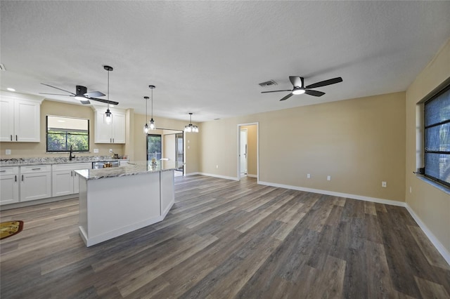 kitchen with light stone countertops, white cabinetry, decorative light fixtures, and dark hardwood / wood-style floors